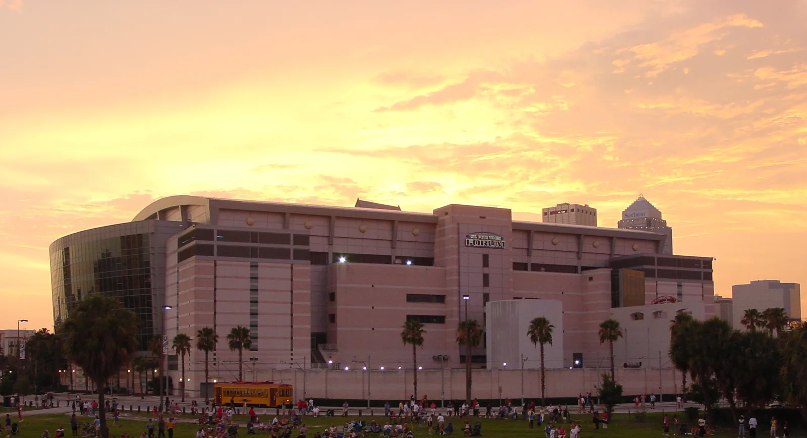 Crowds on the lawn outside the downtown arena now called Benchmark International Arena, with a TECO Line streetcar passing. The building carried an earlier name when the picture was taken.